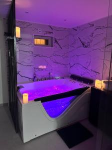 un bagno viola con vasca e illuminazione viola di Love Room 91 avec Jacuzzi XXL - 15min Orly - 30 min Paris a Longjumeau