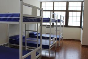 grupa łóżek piętrowych w pokoju z oknami w obiekcie Albergue Folgueira w mieście Portomarin