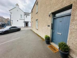 a car parked next to a building with a blue garage at Princes Street Executive Apartment 2 in Thurso