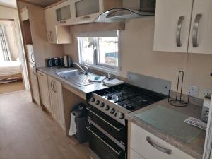 a small kitchen with a stove and a sink at Thames view at Kent Coast Holiday Park in Allhallows
