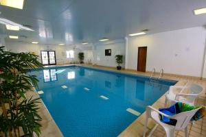 a large swimming pool with two chairs at Hope View - Ashbourne Heights Holiday Park in Fenny Bentley