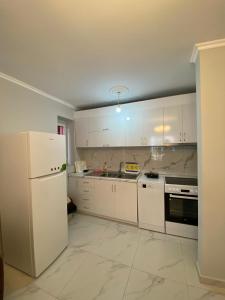 a kitchen with white cabinets and a white refrigerator at Spacious-Central Apartment in Himare
