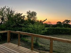a wooden deck with a sunset in the background at Camping à la ferme - Hébergements insolites in Cerisy-la-Forêt