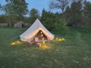 a tent with lights in a field at night at Boutique tent 'Pruum' op een unieke plek in het groen met luxe bed in Vorden