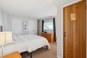 - une chambre avec un lit blanc et une porte en bois dans l'établissement Wintergreen 2 min Village Sauna, à Blue Mountains