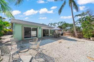 a patio with chairs and a house with palm trees at Tipsy Turtle in Sanibel