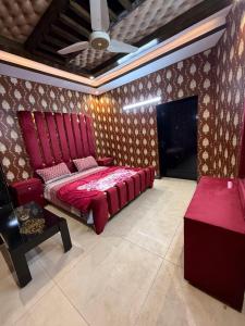 a bedroom with a red bed and a couch and a table at Grand orchard one in Lahore