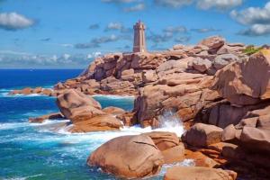 un faro en una orilla rocosa con el océano en Mobilhome, en Louannec