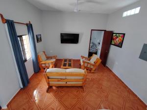 a living room with chairs and a couch and a television at Playa Miel in Telchac Puerto