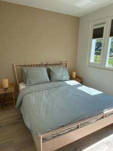a bedroom with a large bed with blue sheets at De Haas - Tiny house in de Zeeuwse Natuur in Driewegen