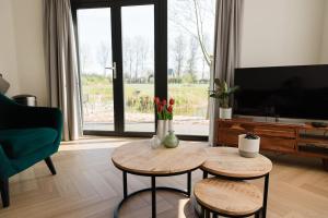 a living room with two tables and a flat screen tv at De Eend - Tiny house in de Zeeuwse Natuur in Driewegen