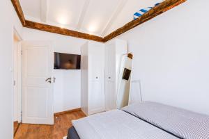 a white bedroom with a bed and a tv at Kuća Koza-Apartment Elisa in Punat