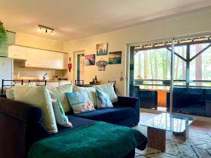 a living room with a blue couch and a kitchen at Golf and Beach Serenity in Aroeira