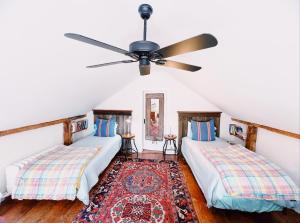 two beds in a room with a ceiling fan at Capt Clarke Historic Homestead Venue in Old Saybrook