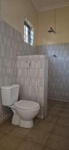 a bathroom with a white toilet and a window at Eagle Nest lake Natron Guest House in Mtowabaga