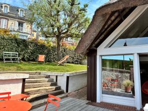 a house with a deck with orange chairs at La petite chaumière sur le rivage in Houlgate