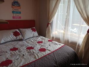 a bedroom with a bed with red flowers on it at Hostal Vista hermosa del Páramo alto, Laguna Verde in Valparaíso