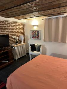 a bedroom with a bed and a chair and a television at Studio 29 m2 proche La Défense et Arena in Nanterre