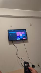 een persoon met een afstandsbediening voor een tv bij Hotel Via Park- NF e Wi-Fi in Campos dos Goytacazes