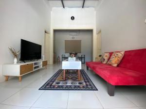 a living room with a red couch and a tv at Rumah Akbar Villa Taliwang in Labuanbalat