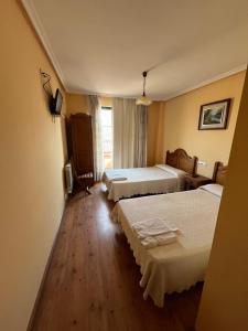 a hotel room with two beds and a television at Hotel Rural El Puente in Mansilla de las Mulas