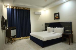 a bedroom with a large bed and a blue curtain at Royalton Inn Hotel - Liberty in Lahore +3 photos