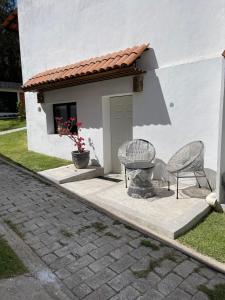 two chairs and a table in front of a building at Departamento en Chapala in Ixtlahuacán de los Membrillos