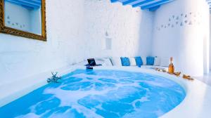 una grande vasca blu in una stanza bianca con uno specchio di Villa Boufla ad Agios Ioannis
