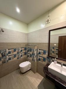 a bathroom with a toilet and a sink and a mirror at Bloom Villa in Guwahati