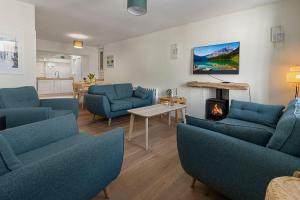 een woonkamer met blauwe stoelen en een open haard bij Picnic Cottage - Family Retreat near Dartmouth in Kingswear