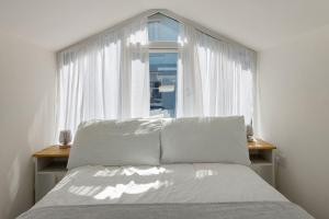 een slaapkamer met een bed en een raam met witte gordijnen bij Picnic Cottage - Family Retreat near Dartmouth in Kingswear