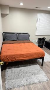 a bed in a bedroom with an orange blanket and a rug at Rooms available in a single Family home shared with Host in Willingboro +10 photos