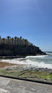 a beach with a group of palm trees and the ocean at Bela vista apartamento Estoril Cascais in Estoril