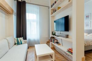 a living room with a white couch and a tv at Apartmán CityPulse in Banská Štiavnica