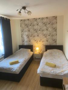 a bedroom with two beds and a wall with a wallpaper at Apartament Mączyńskiego 4 in Jarosław