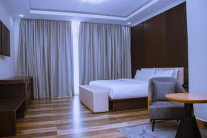 Un dormitorio con una cama, una silla y una mesa. en Essencia Kivu Hotel, en Shangugu