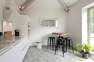 - une cuisine blanche avec une table et des tabourets en bois dans l'établissement Appartement L'Armande, à Arles 31 autres photos