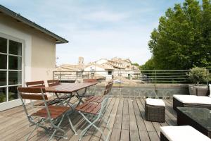 une terrasse en bois avec une table et des chaises sur un balcon dans l'établissement Appartement L'Armande, à Arles