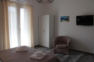 Un dormitorio con una cama y una silla y un televisor. en B&B Aterno, en Montesilvano