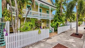 una recinzione bianca di fronte a una casa con palme di Barbuda Suite by Last Key Realty a Key West