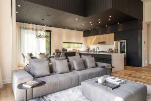 a living room with a gray couch and a kitchen at NEW! Chalet Aurora 5 Bedrooms Hot tub Outdoor Pool in La Conception