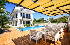 a villa with a swimming pool and a yellow umbrella at Meva Luxury Apartments in Muğla