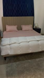 a large white bed with pink pillows on it at Raheem luxury 3 bedroom in Jabang +13 photos