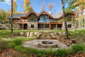 ein Blockhaus mit einer Feuerstelle davor in der Unterkunft Grand Foret Villa Luxurious Chalet with Hot Tub and Outdoor Firepit in Mont-Tremblant