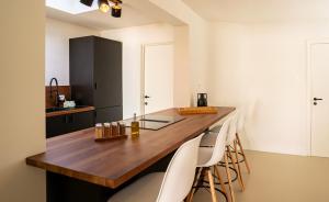 une cuisine avec un comptoir en bois et des chaises blanches dans l'établissement Maas Suites - The River House with private sauna, à Lanaken