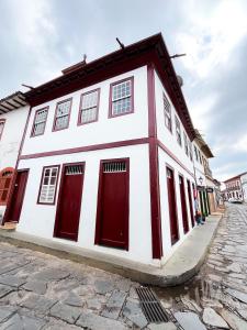a white building with red doors on a cobblestone street at Solar Lages - Diamantina - MG in Diamantina