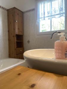 a bathroom with a tub and a sink with a bottle of soap at Mer et Campagne, maison entourée d'un jardin privé in Quend
