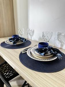 a wooden table with two plates and glasses on it at RiverSide 101 in Petrolina