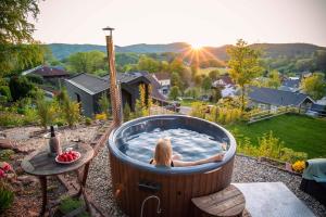 a woman sitting in a hot tub in a yard at Ferienwohnung Weitblick im Dahner Felsenland in Bruchweiler-Bärenbach