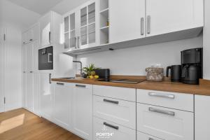 a kitchen with white cabinets and a wooden counter top at Ferienwohnung Kleine Welle Westerland auf Sylt in Westerland (Sylt)